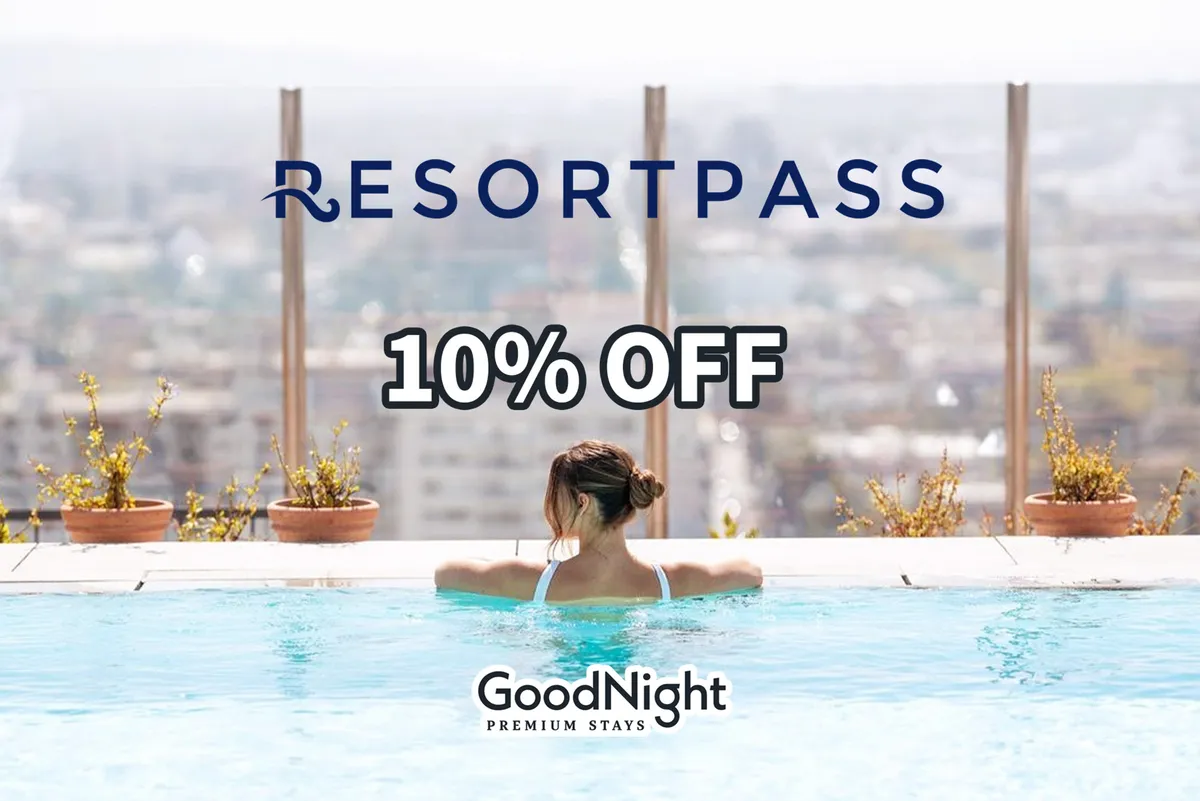 A tranquil swimming pool with a view of the city skyline in the background. A woman relaxes in the water, enjoying the sunset and the urban vista, encapsulating a balance of work and relaxation.