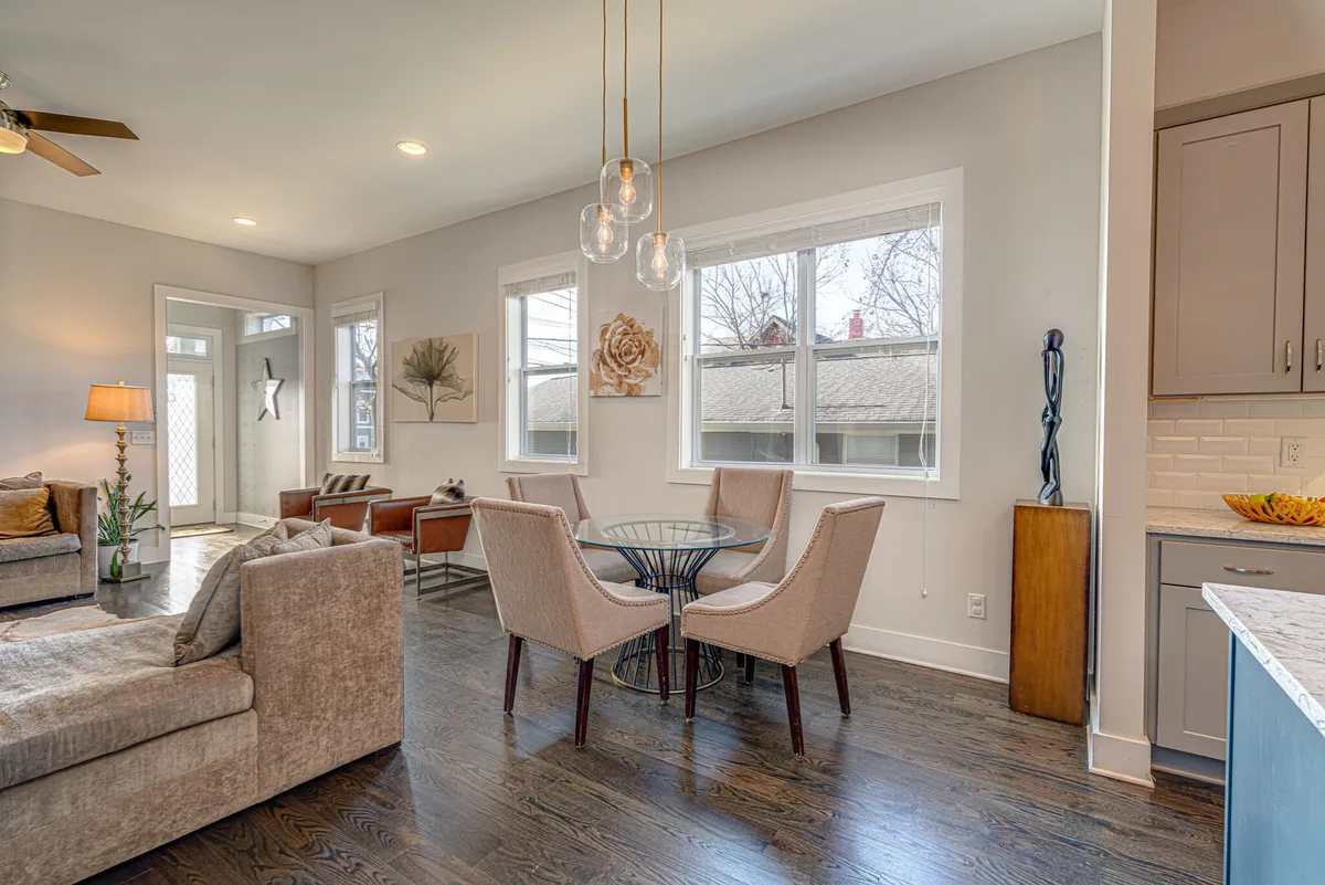 A cozy dining area featuring a modern dining table with comfortable chairs, warm pendant lights, and a plush sofa nearby. Stylish artwork and welcoming decor create an inviting ambiance for meals and conversation.