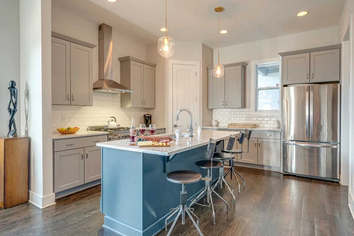 A sleek, up-to-date kitchen with a central island, stainless steel appliances, stylish light fixtures, and an artistic sculpture. It feels ready for both casual meals and entertaining, highlighting the thoughtful setup for guest needs.