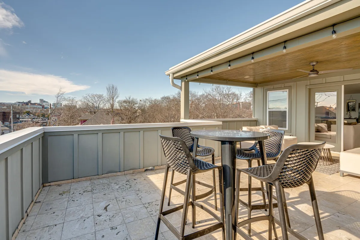 A sleek rooftop high-top table setup with bar stools and a panoramic view, ideal for outdoor dining or drinks. The rooftop is bathed in soft evening light, suggesting a relaxed, social atmosphere suitable for brunches or sunset gatherings.
