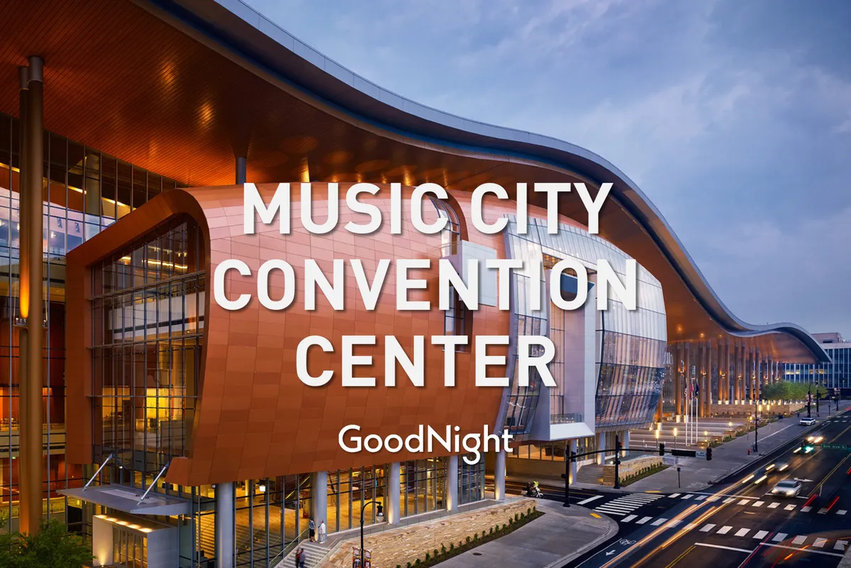 This image features a prominent, modern convention center with a curved architectural design, large glass windows, and welcoming warm lighting. The scene is energetic and bustling, suggestive of conferences, exhibitions, and business gatherings.